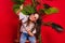 A little girl with round sunglasses stands next to a palm tree on a solid red background. A cheerful and energetic child