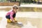 a little girl in rubber boots launches a paper boat in a large puddle