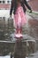 Little girl in rubber boots, playing in small puddle after rain