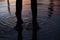 Little girl in rubber shoes stands in puddle.