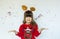 Little girl in rudolf hat waiting for a Christmas on white background.