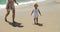 Little girl running along a beach with her mother