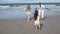 Little girl running on beach into her parents open arms