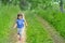 Little girl running in sunny blooming forest. Kids play outdoors. Summer fun for family with children.