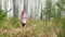 A little girl runs along a path in a birch forest.