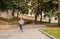 A little girl runs along the sidewalk in the park. Active play in nature. The girl laughs and is happy