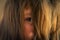 A little girl`s gaze through her long hair. Close-up of the child`s eye.The young witch is furious