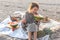 Little girl on the sandy seashore at a picnic with fruits.
