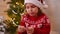 A little girl in a Santa hat opens a fortune cookie. Traditional Christmas fun for children and adults.