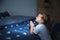 Little girl saying bedtime prayer near bed in room