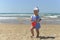 A little girl in a scarf playing on the sandy beach