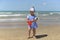 A little girl in a scarf playing on the sandy beach