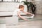 A little girl of school age does sports exercises on a gymnastic carpet on the floor. Nearby is a laptop, there is a video with