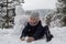 Little girl sculpts snowman in winter snowy Park.