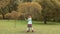 Little girl shaking a tree in the autumn park