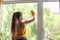 Little girl in shirt and blue shorts washes the windows at home. Daughter with a cat wash the window