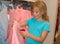 Little girl shopping in clothes store. Child chooses dress at clothes shop.