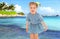 Little girl in a short blue dress on a sea background.