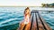 A little girl in shorts and a T-shirt sits on a pier by the lake in summer. Summer vacation