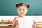 little girl showing exam paper with a plus in classroom