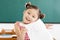 little girl showing exam paper with a plus in classroom