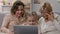 Little girl showing funny video on laptop to mom and granny, humorous show
