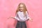 Little girl shows emotion I donï¿½t know. surprised schoolgirl in uniform. pink background