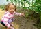 The little girl shows green fruits of tomatoes in the greenhouse