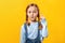The little girl shows with index finger up on an empty place. The child on a yellow background. Copy space