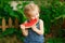 Little girl sit on watermelon and eating pieces