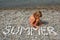 Little girl sits on beach near to water.