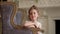 The little girl sits in a big chair. The little ballerina looks in a distance. The girl sits in a chair