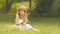 Little girl sits in a clearing, turns over the torn wild flowers and makes a bouquet from them