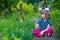 Little girl sits in flowers in the park and points at something