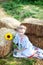 Little girl sits on roll of haystacks in garden. child sits in straw and enjoying nature on a fall day in countryside. Sunflower.