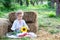 Little girl sits on roll of haystacks in garden and holds sunflower. A child sits on straw and enjoys autumn nature in countryside