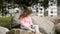 A little girl sits on the stones in the park and watches cartoons on a smartphone