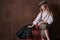 Little girl sits on suitcases. vintage style photography. child in a white shirt, pants and a hat with a visor. studio. brown