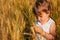 Little girl sits on wheaten field