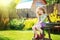 Little girl sits on a wooden chair in the yard of a country house.