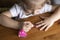 little girl sits at a wooden table and paints nails with nail polish