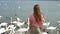 Little girl sitting on the beach with swans