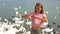 Little girl sitting on the beach with swans