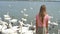 Little girl sitting on the beach with swans