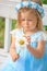 Little girl sitting on a bench in a blue dress with a chamomile