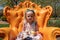 Little girl sitting in a bright orange chair in a garden