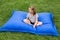 Little girl sitting cross-legged on giant blue exterior cushion