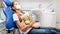 Little girl sitting in dentist chair with toy teddy bear in clinic