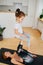 Little girl sitting on a feet chair, doing gymnastics with her mother