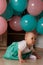 Little girl sitting on the floor in the room next to the balloons, first birthday, celebrate. one year old blue and pink balls wit